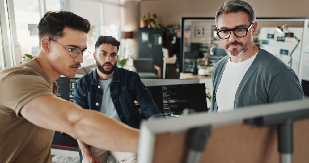 Photo of a team of external developers who are looking at a computer screen to represent outsource software.