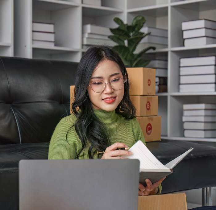 Picture of a female business owner using an e-commerce website, surrounded with a few packages to represent e-commerce developer.