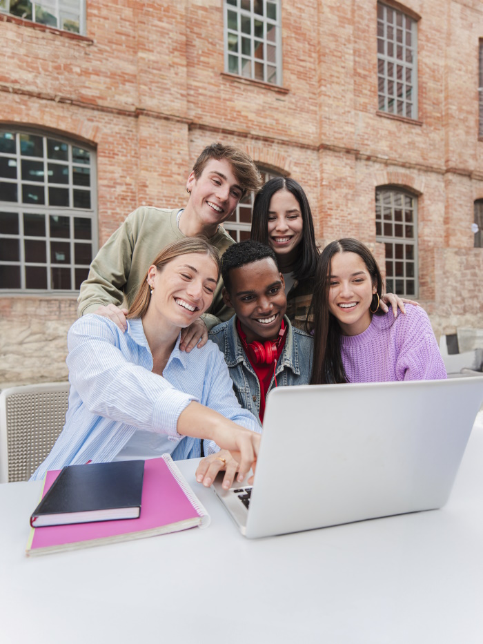  Photo of students around a laptop.