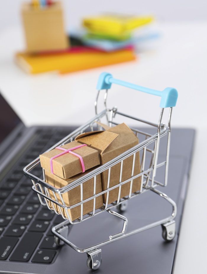 Photo of a tiny shopping cart stood on a laptop.