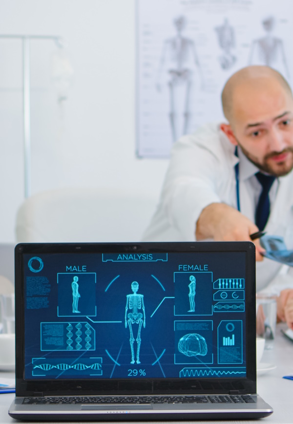 Photo of a male medical staff behind a laptop screen using modern healthcare software.