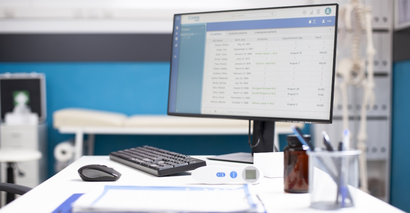 Photo of desk and monitor and keyboard with healthcare software on the screen.
