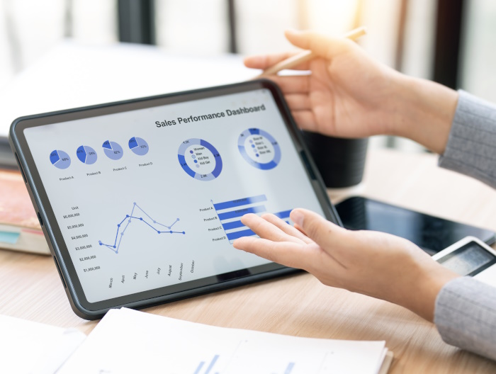 Photo of female hands holding a tablet, running reporting software.