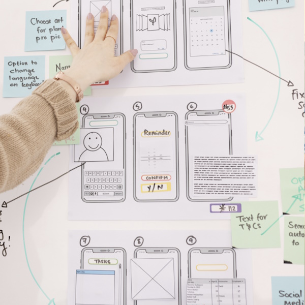 Photo of a hand pointing to wireframes on a whiteboard.